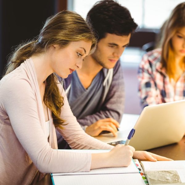 Focused classmates studying together and using laptop